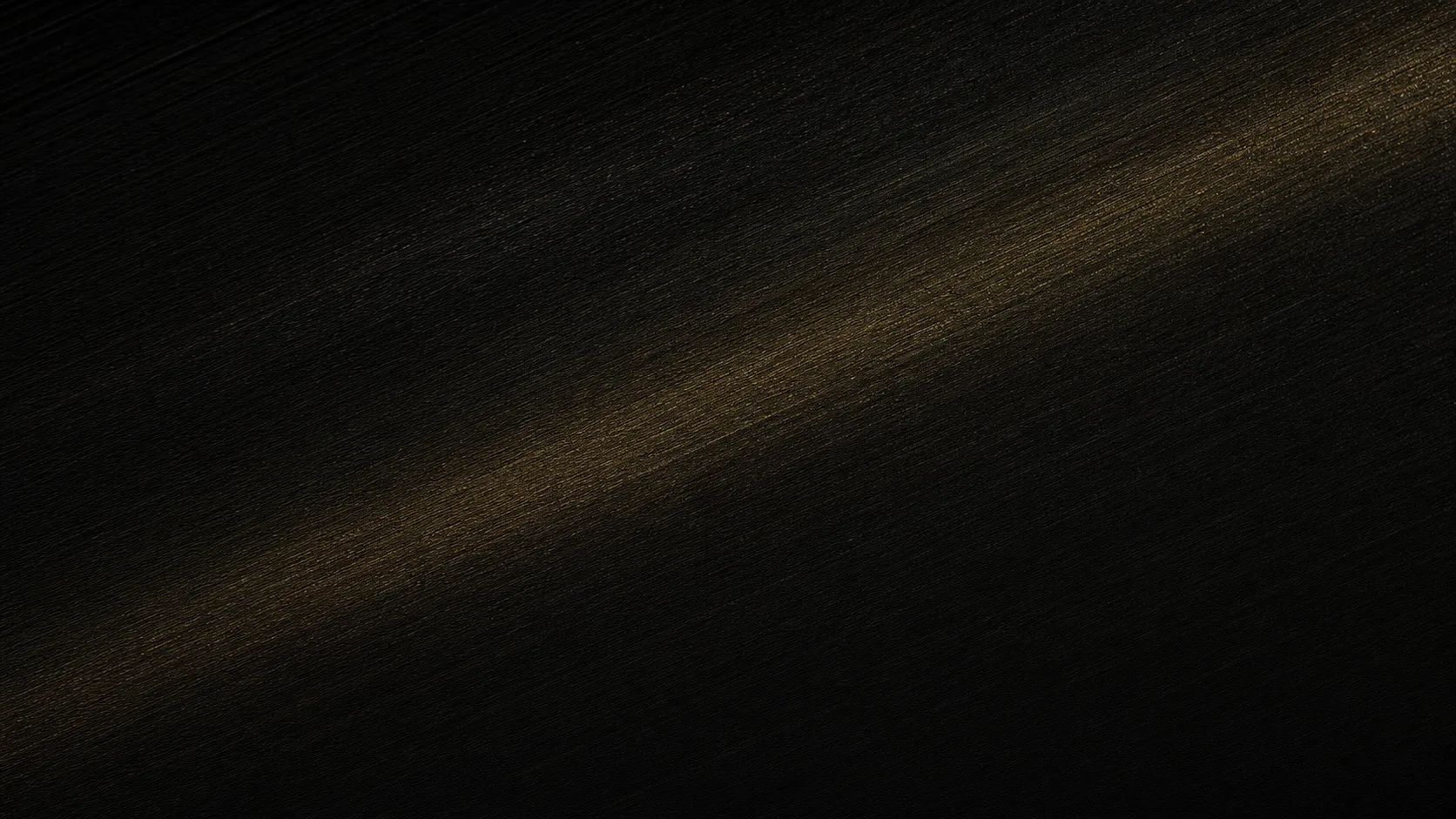 Macro study of brushed black metal crossed by a warm gold reflection