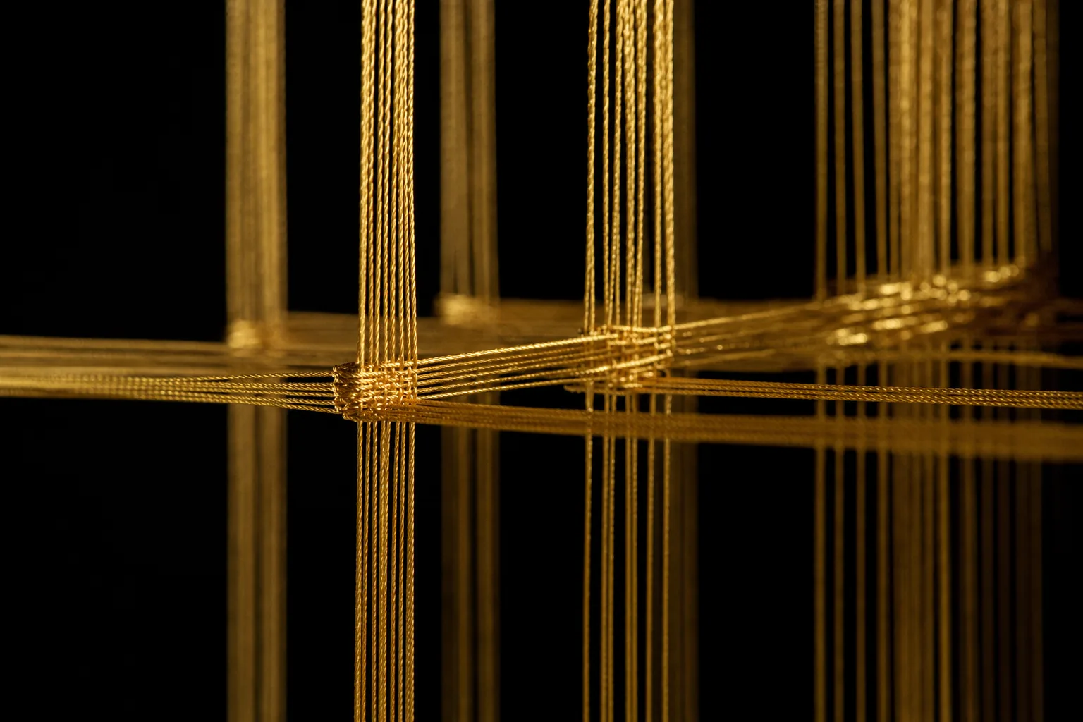 Gold threads woven into a precise lattice, lit from a single warm source